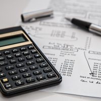 房贷计算栏目编辑整理公积金与组合贷资料，桌面上摊开多份额度测算草稿与计算器，暖色台灯照明
